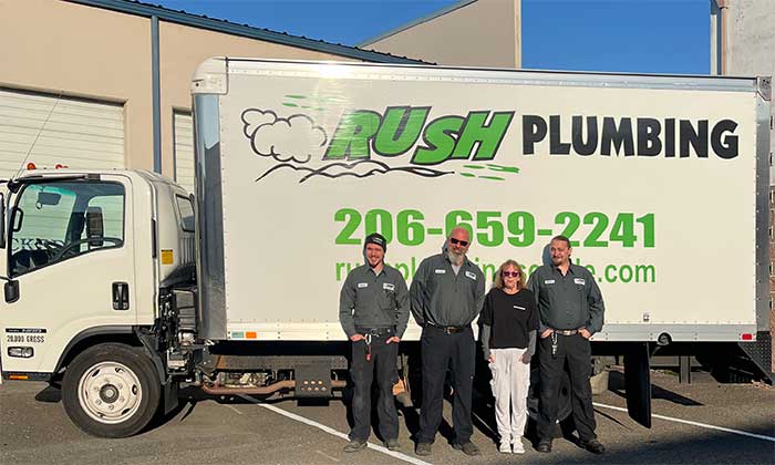 Rush Plumbing van with 3 men and one woman standing in front of it